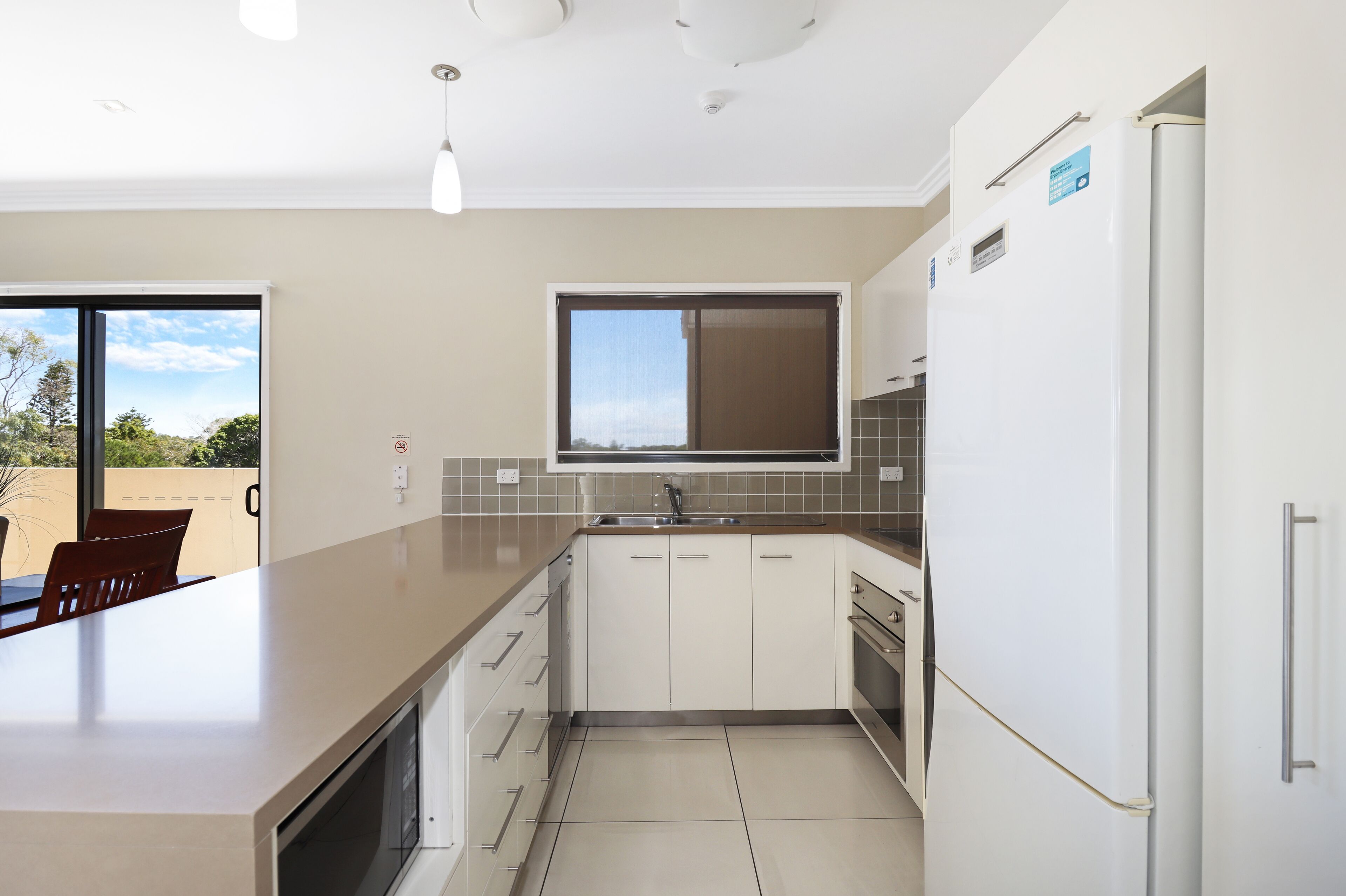 Una cocina moderna con armarios blancos, una isla grande y un horno empotrado.