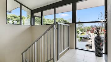 A modern interior with a staircase, large windows, and a potted plant.