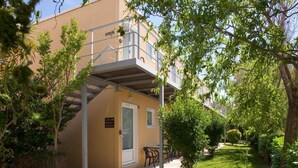 A building with a covered outdoor seating area, a door, and a sign with text. - Top Motel (Istres)