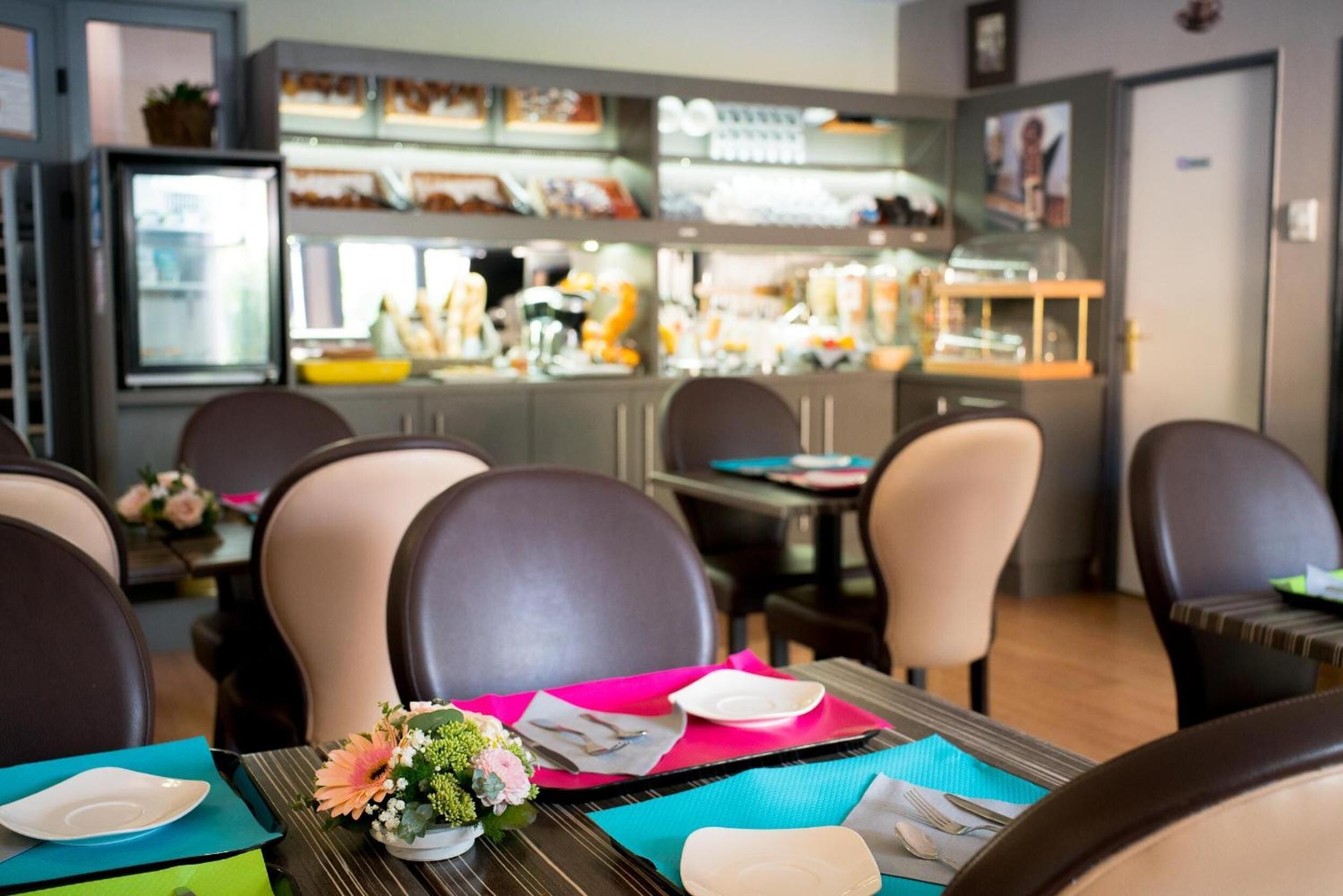 Un interno di ristorante con tavoli apparecchiati, sedie e un bancone con diversi cibi.
