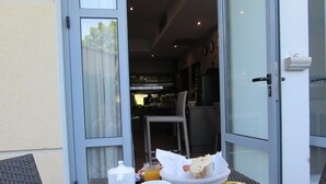 A breakfast tray with bread, juice, and a coffee pot on a table outside a building. - Top Motel (Istres)