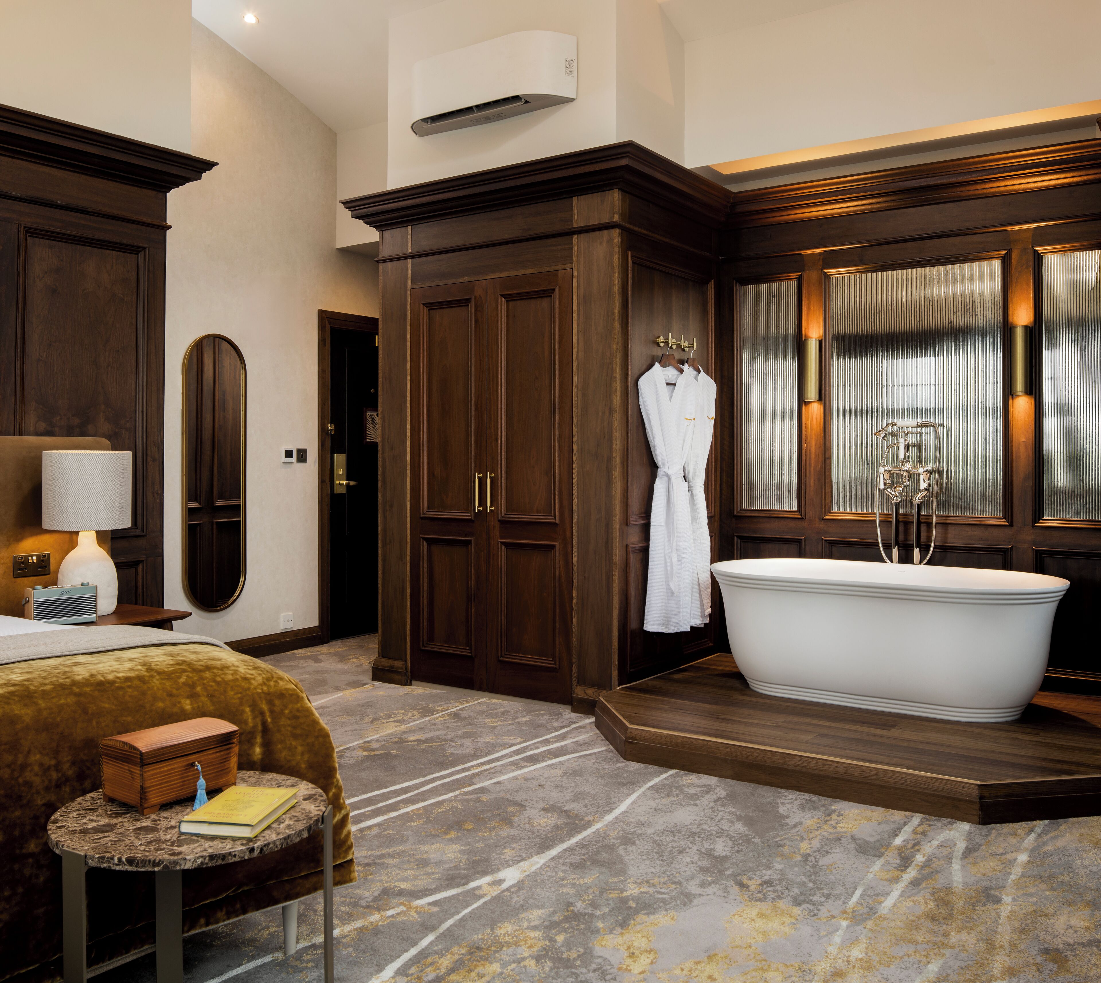 A spacious bathroom with a freestanding bathtub, a large mirror, and wooden cabinetry.