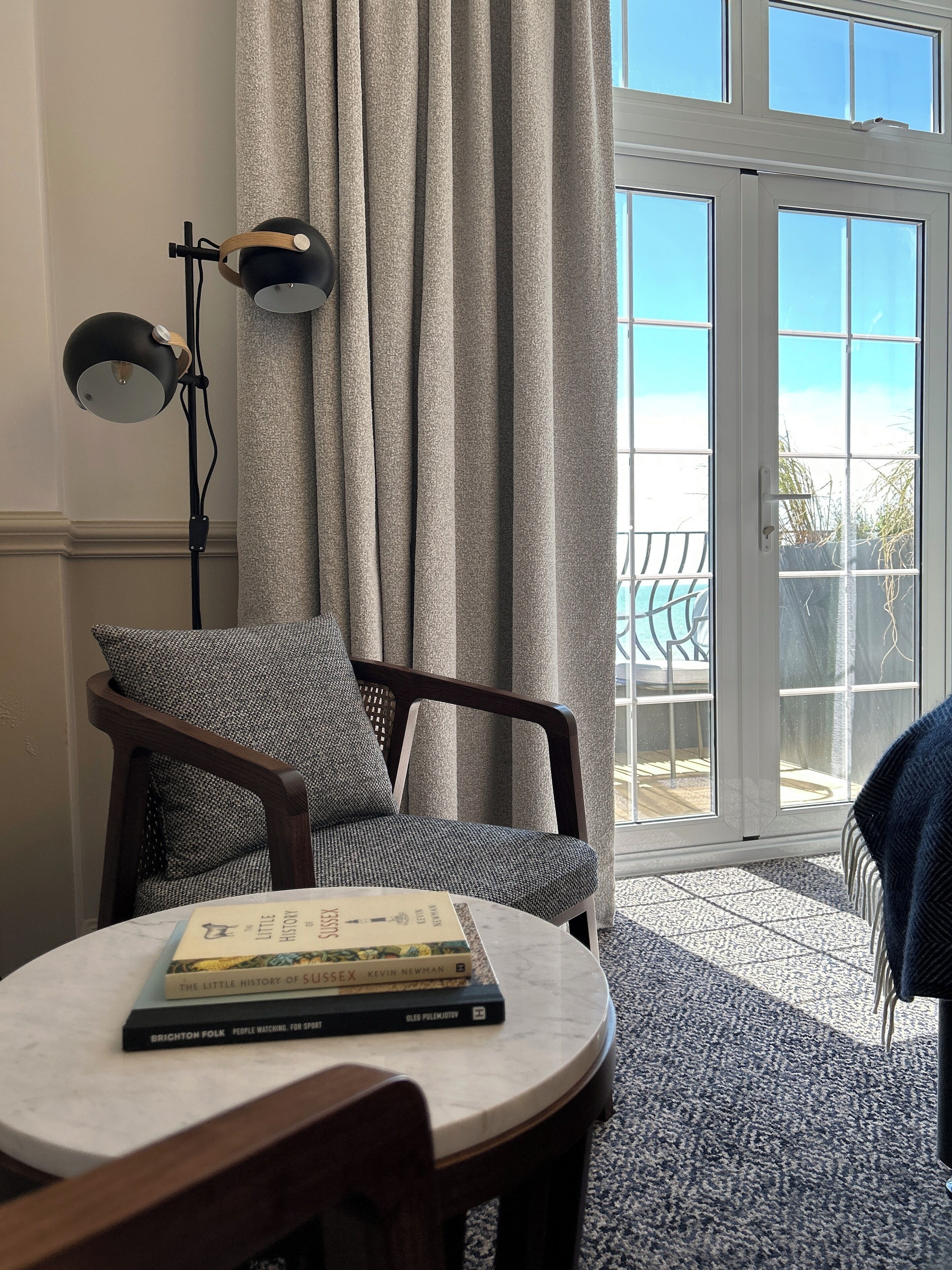 A cozy room with a round table, a chair, a lamp, and a bookshelf with books.