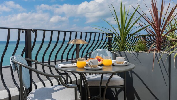 A balcony with a table set for breakfast, overlooking the sea. - White Horses by Everly Hotels Collection (Brighton)