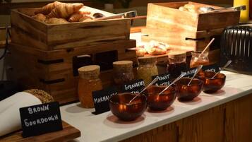 A breakfast buffet with croissants, muffins, and various jams and spreads.