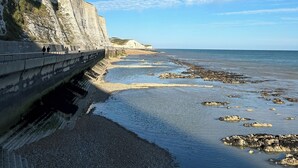 A coastal walkway with a steep cliff on one side and a beach on the other. - White Horses by Everly Hotels Collection (Brighton)