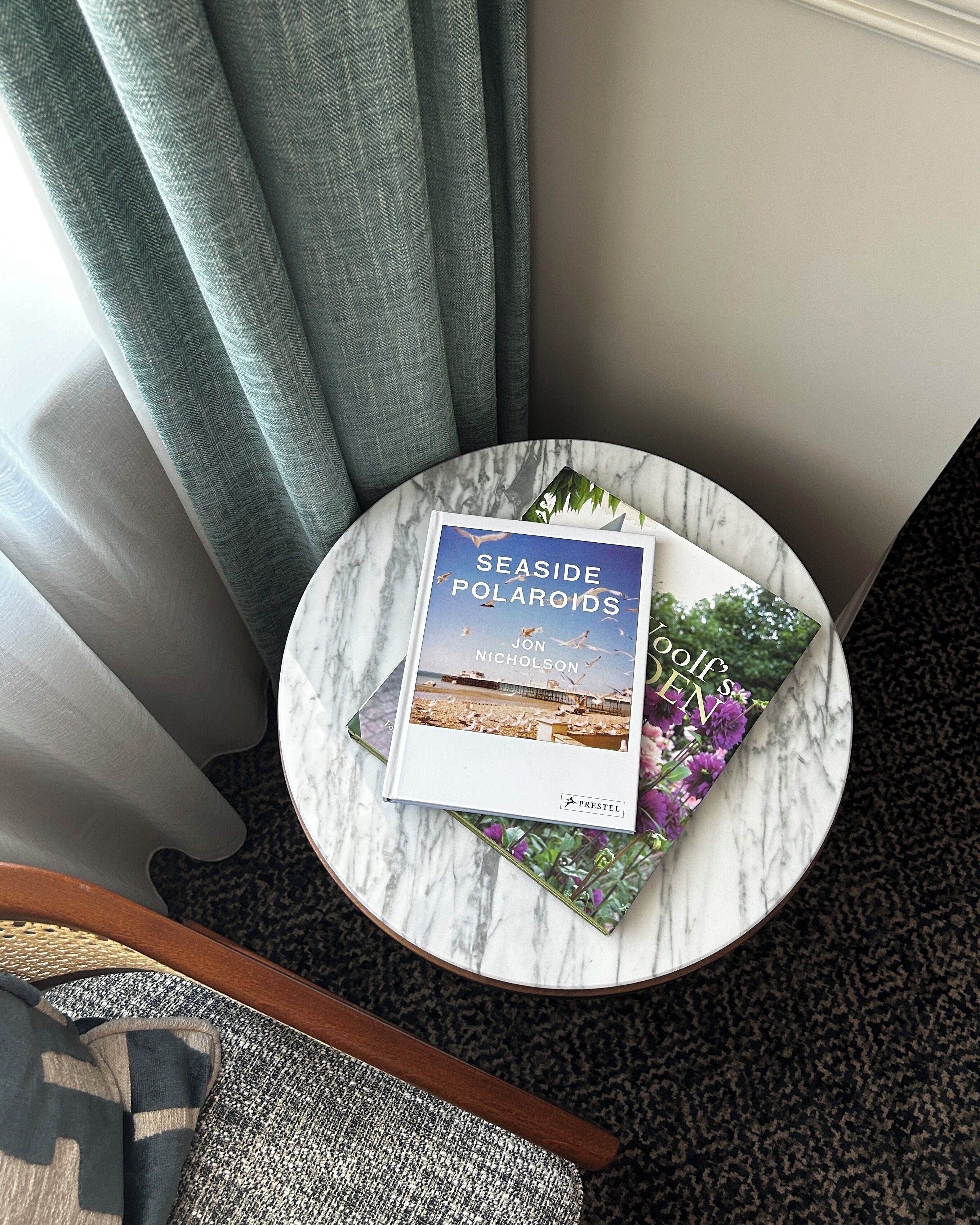 A book titled 'Seaside Polaroids' by Jon Nicholson on a marble table.