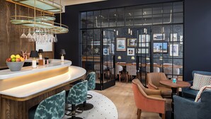 A modern bar area with a curved countertop, bar stools, and a wine rack. - White Horses by Everly Hotels Collection (Brighton)