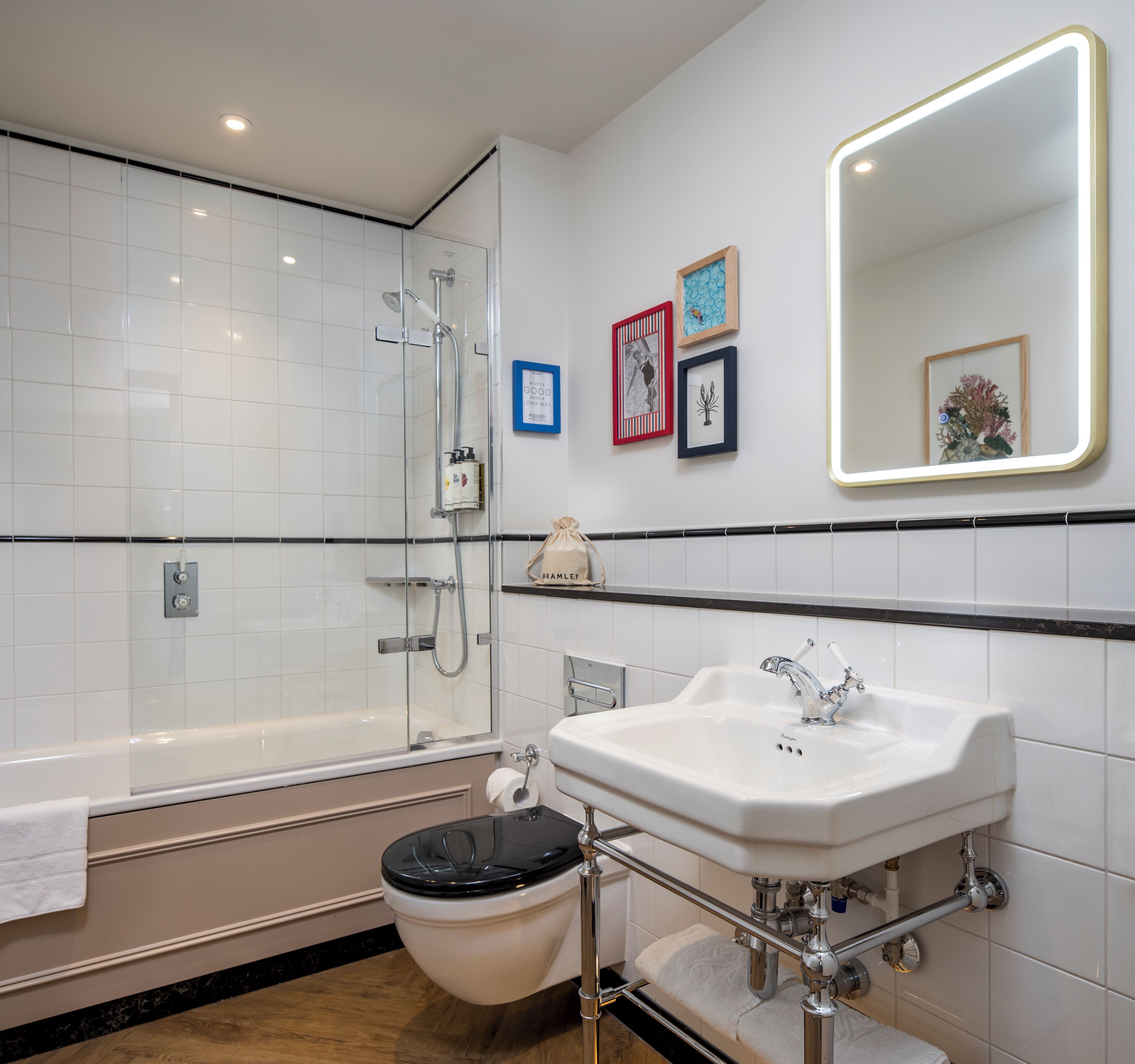 Un baño moderno con ducha de vidrio, lavamanos blanco y un inodoro.