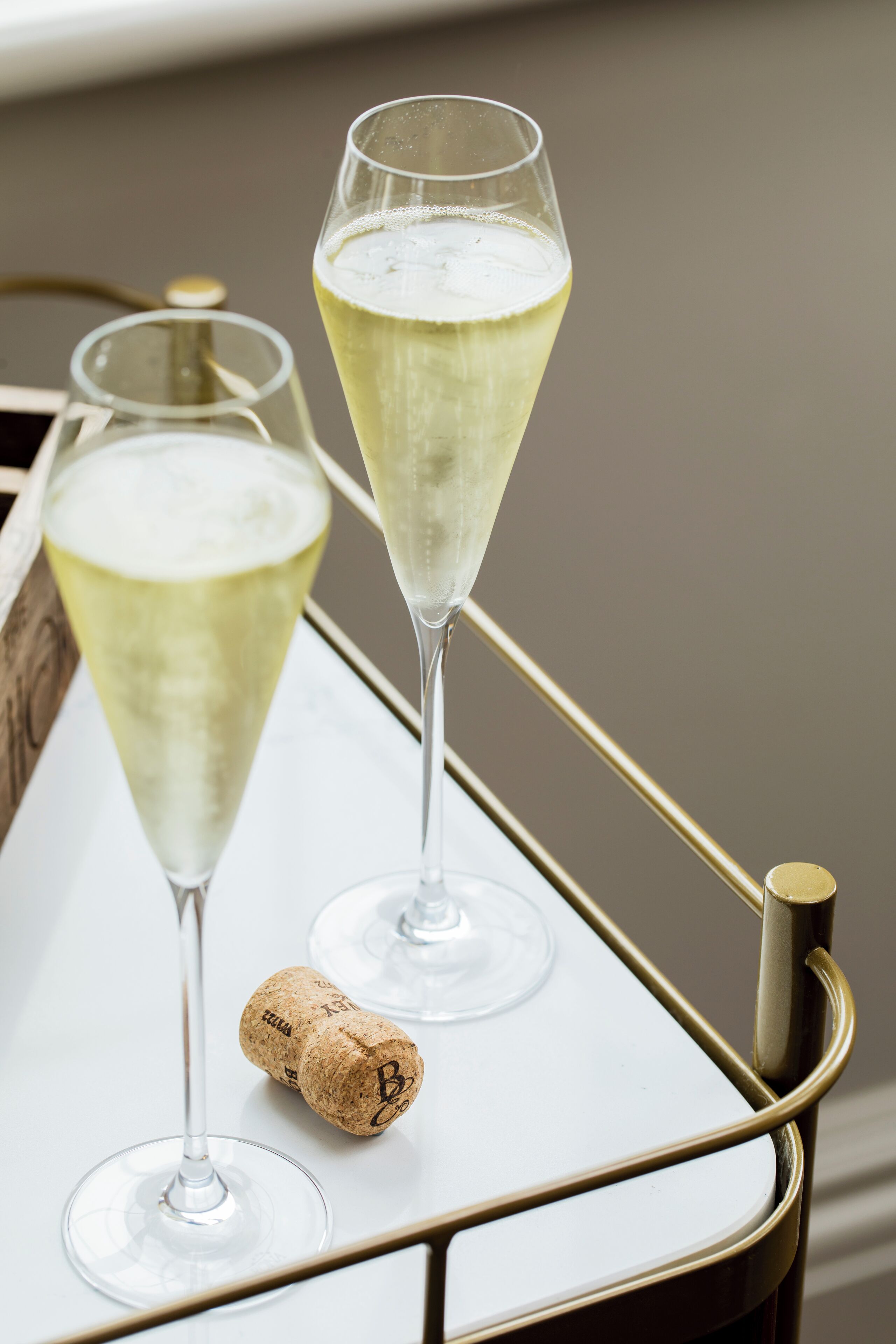 Twee champagneglazen op een dienblad met een kurk.