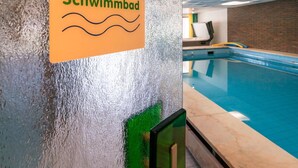 A sign reading "Schwimmbad" on a textured wall, indicating a swimming pool area. - Aparthotel Hochwald (Bad Liebenzell)