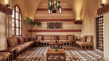 A spacious lounge with a high arched ceiling, a patterned floor, and a central seating area with a coffee table.