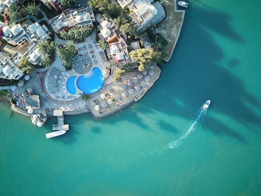 An aerial view of a resort with a central pool, a boat dock, and a surrounding water body.