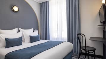 A hotel room with a large bed, a chair, a desk, and a TV.