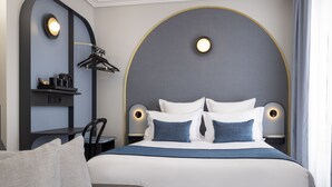 Una habitación de hotel moderna con una cama grande, una mesita de noche, una silla y un escritorio con silla.