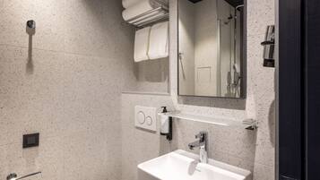 Un baño moderno con un lavabo blanco, un espejo y un perchero para toallas.