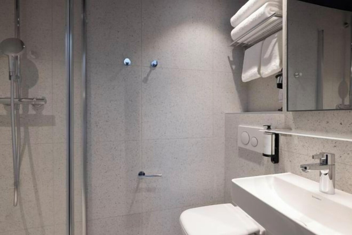 A modern bathroom with a glass shower enclosure, a white sink, and a toilet.