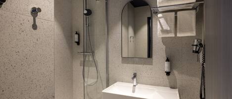 A modern bathroom with a shower, sink, and towel rack.