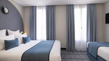 A hotel room with two beds, a large window with curtains, a flat-screen TV, and a patterned carpet.