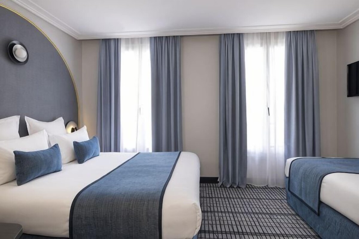 A hotel room with a large bed, two smaller beds, a flat-screen TV, and a large window with curtains.