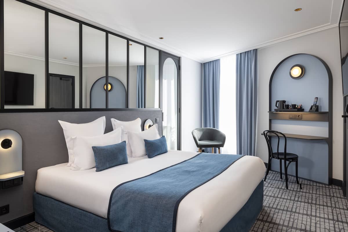 Ein modernes Hotelzimmer mit einem großen Bett, einem Schreibtisch und einem Stuhl.