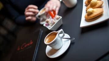Une table avec une tasse de café, une assiette de pâtisseries et un petit récipient de sucre.