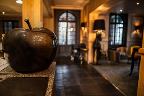 A modern interior with a large bronze sculpture on a counter, a grand arched doorway, and elegant lighting fixtures. - The Originals Boutique, La Maison Rouge (Noeux-les-Mines)