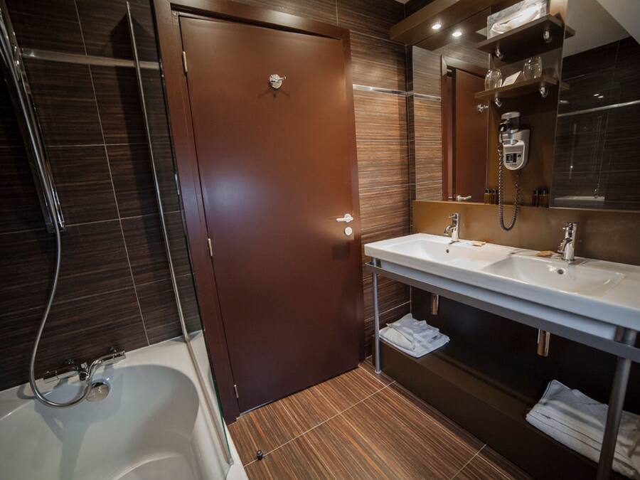 A modern bathroom with a bathtub, two sinks, a shower, and a towel rack.