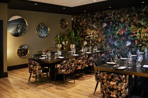 A dining area with a long table set for multiple people, surrounded by chairs with floral upholstery. - The Originals Boutique, La Maison Rouge (Noeux-les-Mines)