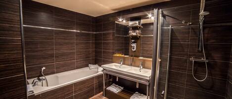 Un baño moderno con bañera, dos lavamanos, ducha envuelta en vidrio y paneles de madera oscura.