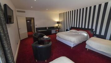 A hotel room with two beds, a desk, a chair, and a small table.