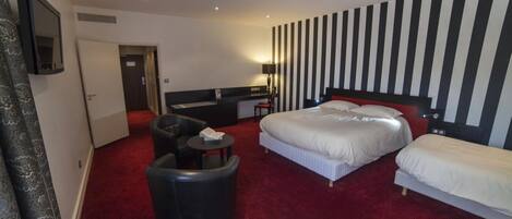 A hotel room with two beds, a desk, a chair, and a small table.