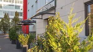 Uma área de recepção com um letreiro, plantas em vasos e um pilar vermelho.