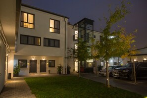 A modern building with multiple doors and windows, a small lawn, and parked cars. - Goethe Hotel Messe by Trip Inn (Frankfurt)
