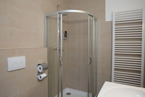 A modern bathroom with a glass-enclosed shower, a toilet paper dispenser, and a towel rack. - Goethe Hotel Messe by Trip Inn (Frankfurt)