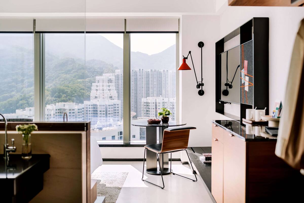 A modern kitchen with a large window, a dining area, and a TV mounted on the wall.