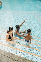 A swimming pool with tiled flooring and a person sitting on the edge.