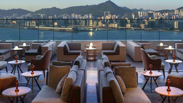 Eine Dachterrasse mit Sofas und Tischen mit Blick auf Stadt und Wasser.