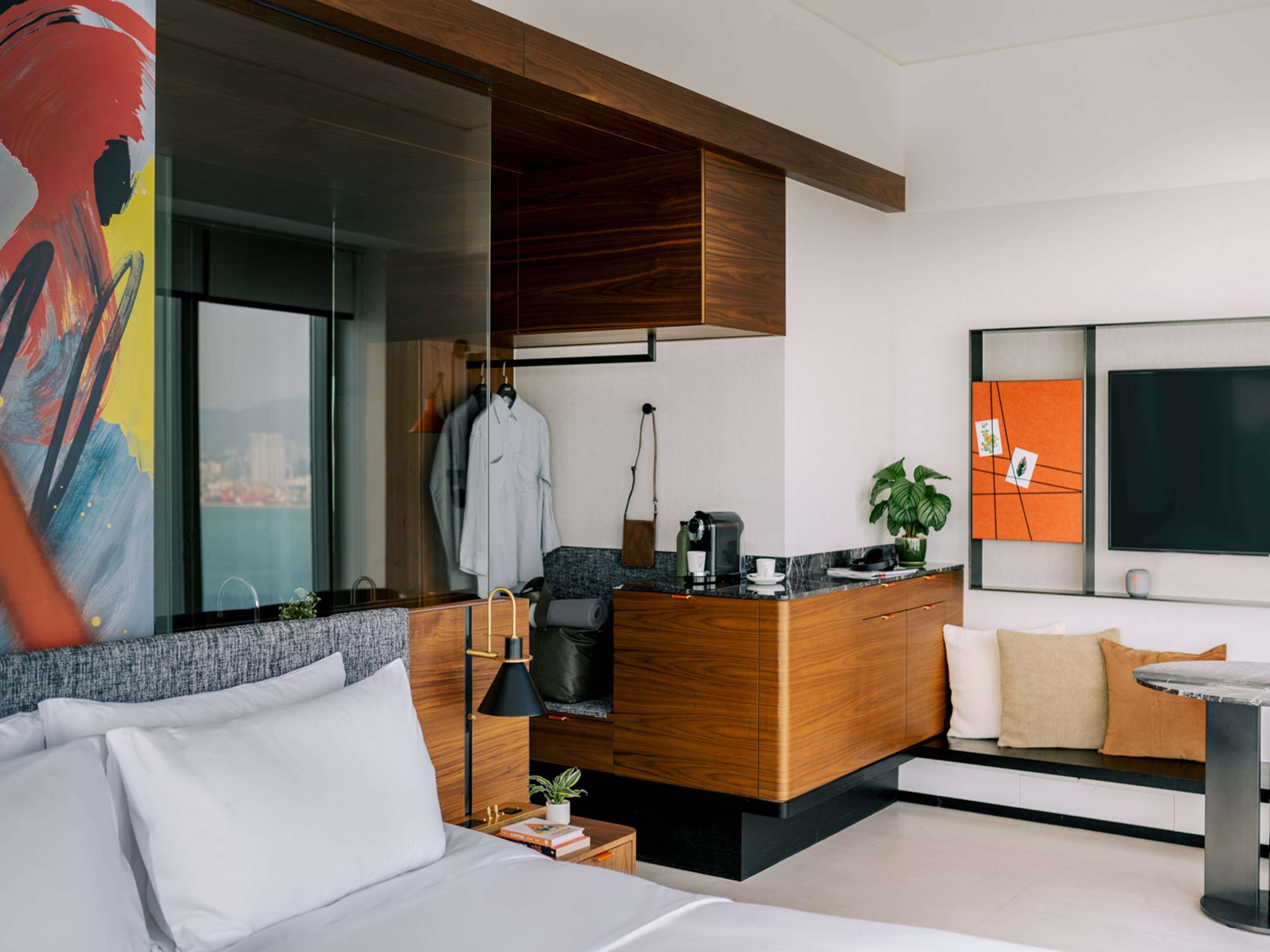 Ein modernes Hotelzimmer mit Bett, Sofa, Holztisch und großem Fenster.