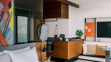 Ein modernes Hotelzimmer mit Bett, Sofa, Holztisch und großem Fenster.