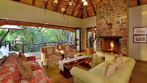A cozy living room with a stone fireplace, comfortable seating, and a view of the outdoors.