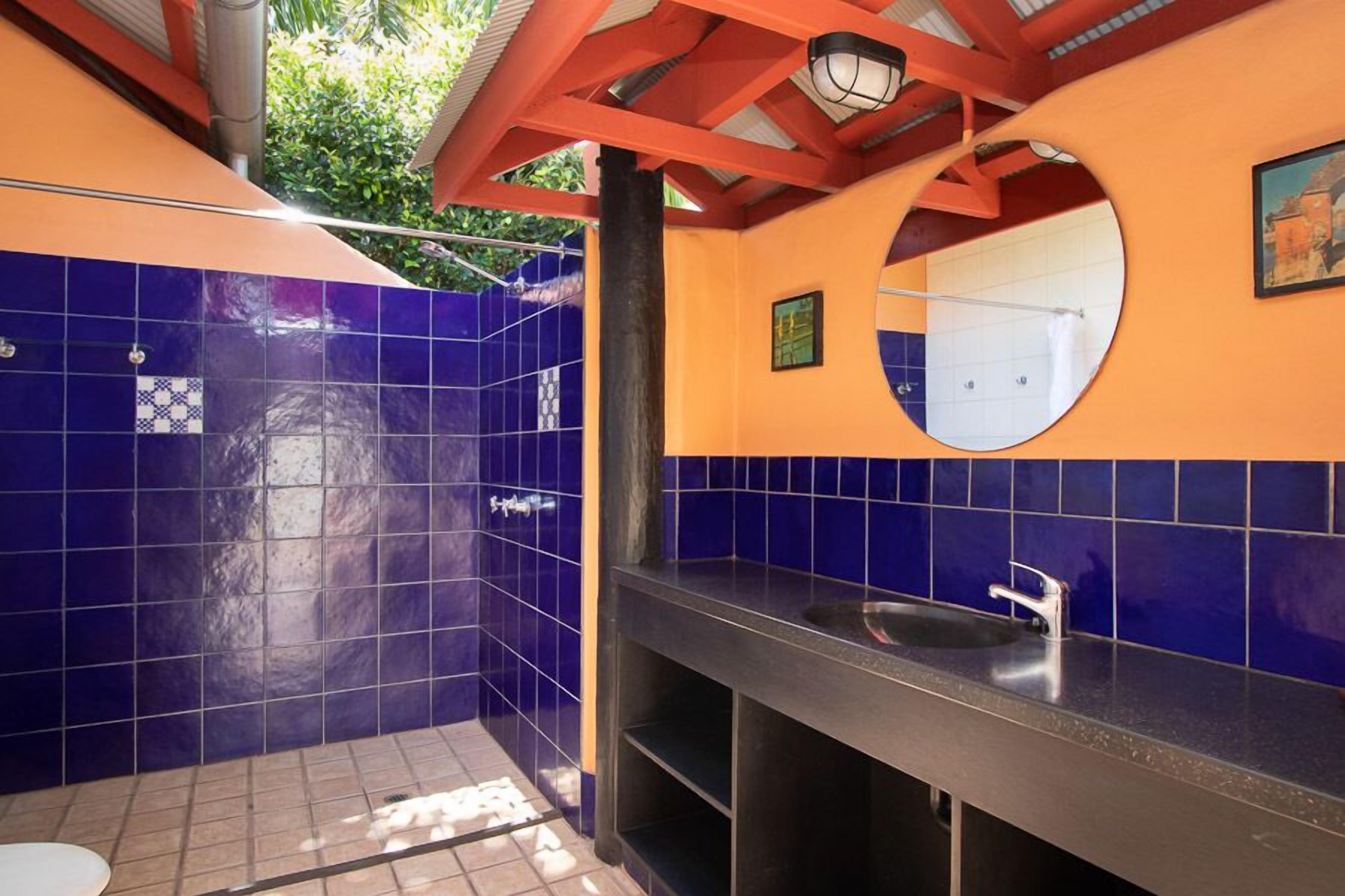 A bathroom with blue tiles, a sink, and a mirror.
