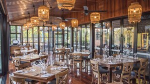 A restaurant with wooden tables and chairs, large windows, and hanging wicker light fixtures. - Bali Hai Resort & Spa (Cable Beach)