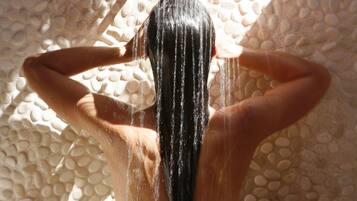 A person standing under a shower with water flowing down.