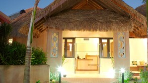 A resort with a thatched-roof entrance, a reception desk, and a well-maintained garden with palm trees. - Bali Hai Resort & Spa (Cable Beach)