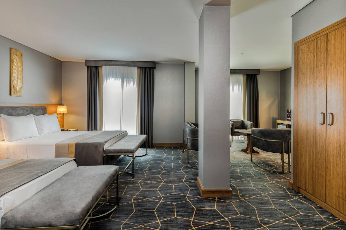 A hotel room with a bed, a desk, a chair, and a wardrobe.