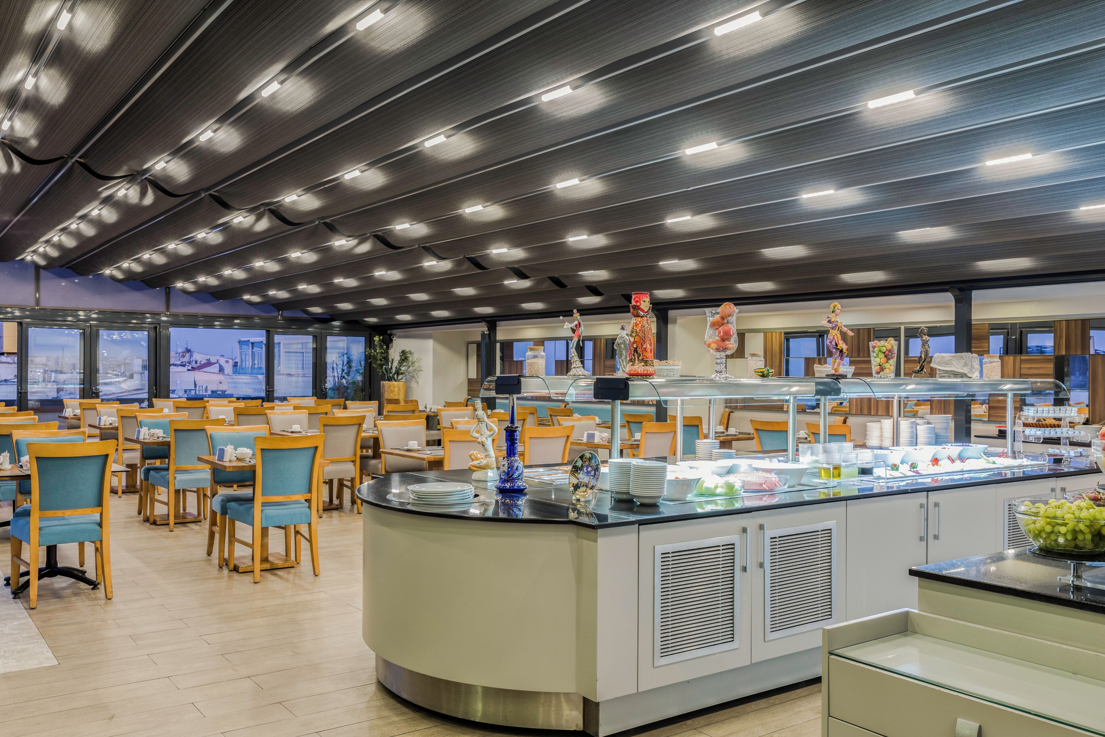 Ein modernes Restaurant mit Buffet, ausgestattet mit einer zentralen Insel zur Präsentation der Speisen und Sitzgelegenheiten darum herum.