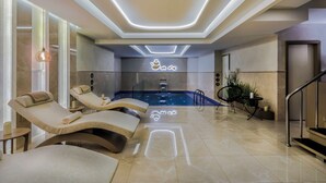 Un área de spa moderna con sillones reclinables, una piscina y una recepción.