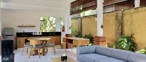 A spacious living area with a dining table, sofa, and a kitchen in the background.