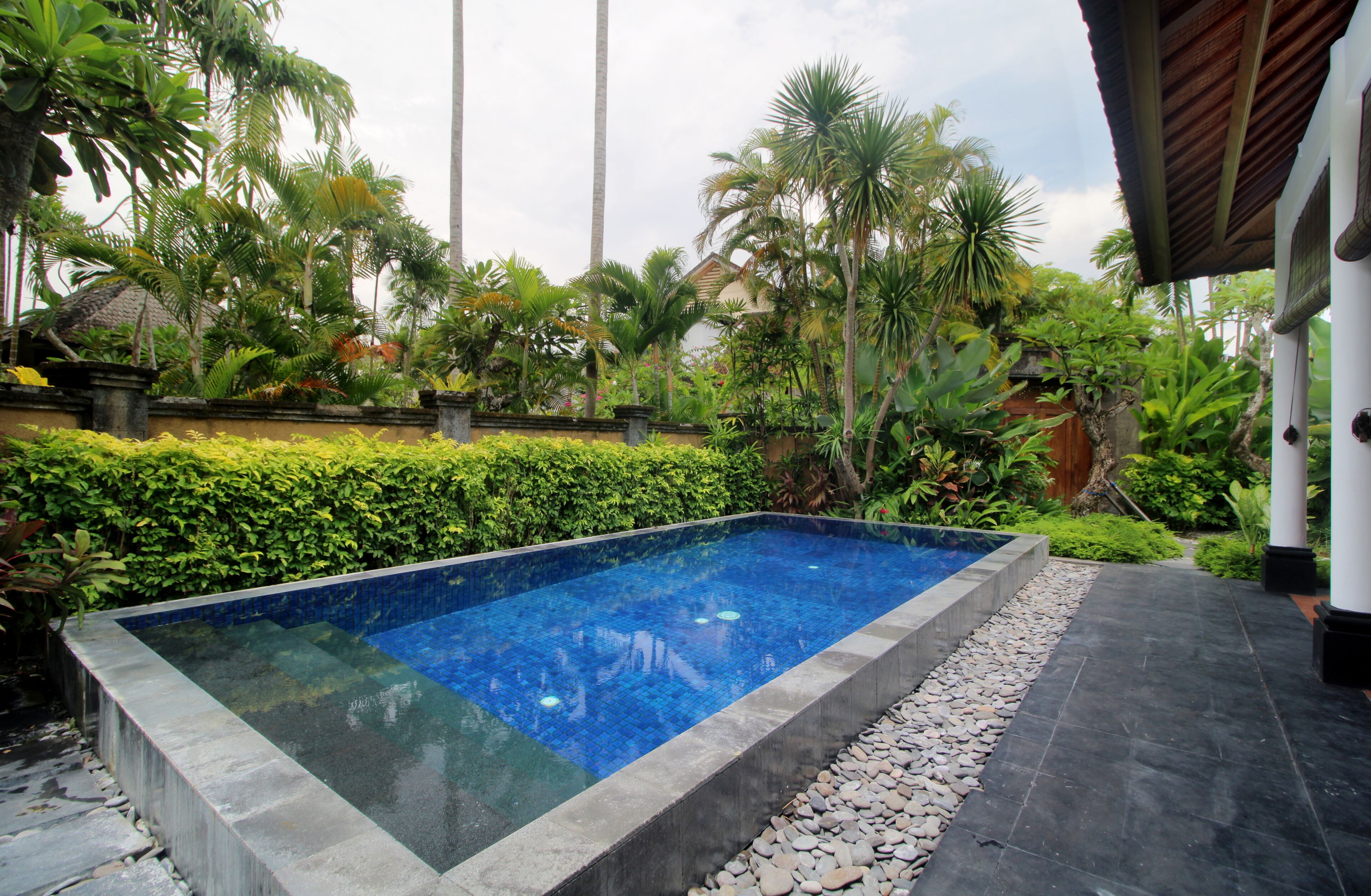 A rectangular swimming pool with a tiled edge, surrounded by a stone border and a pebble bed.
